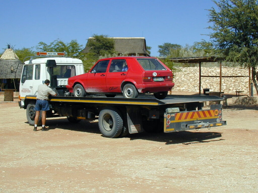 Red Volkswagen Chico on top of a tow truck