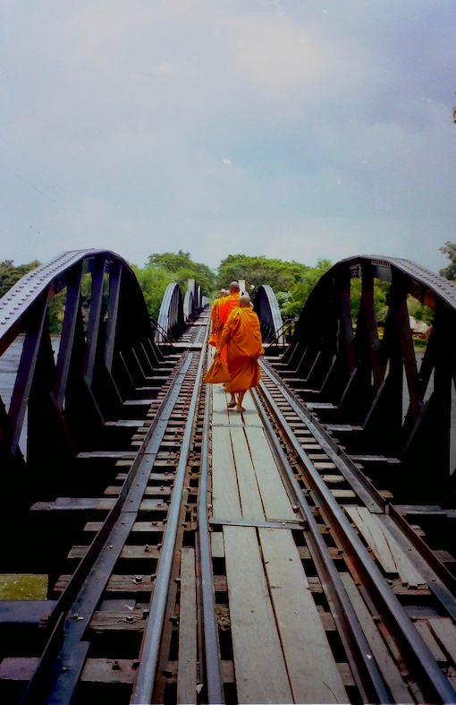 Thai monks walking across a bridge