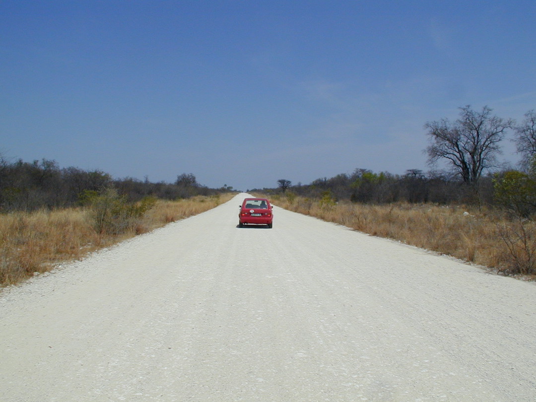 Red Volkswagon Chico car driving on a gravel road in Namibia