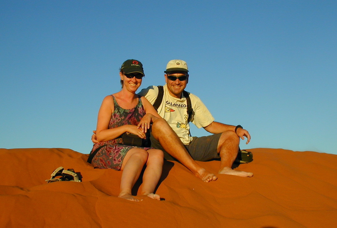 Sharon and David Schindler sitting on top of a red sand dune in Namibia